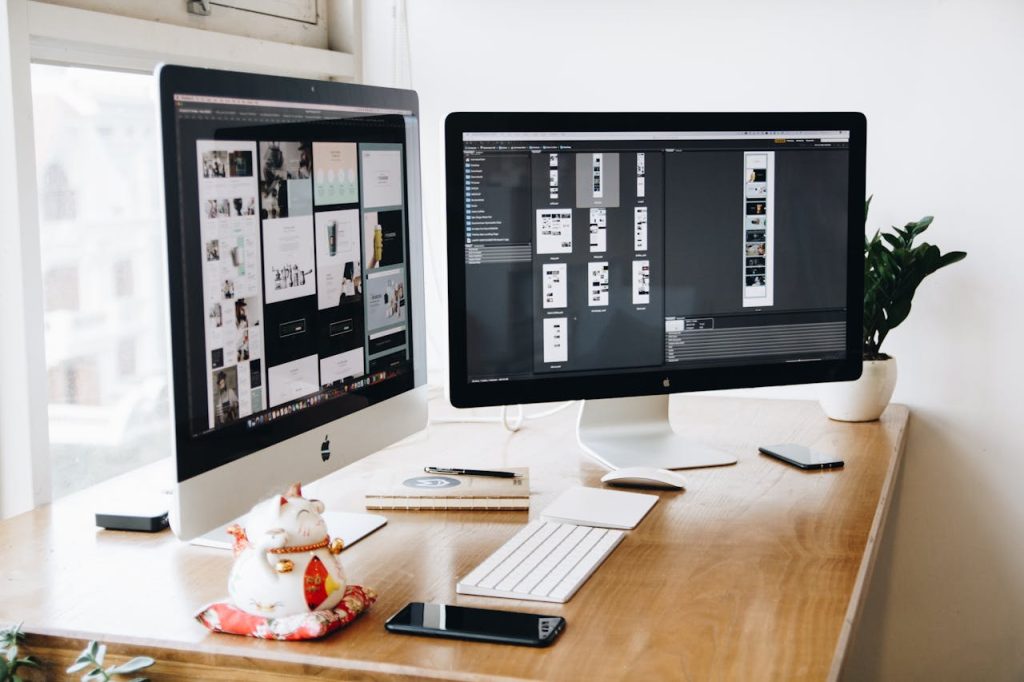 Espace de travail de designer bien organisé avec double écran affichant un logiciel de création graphique