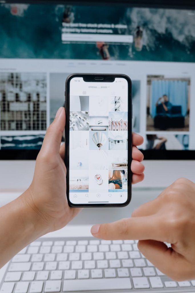 Personne consultant des photos sur smartphone dans un environnement de bureau moderne, illustrant la compatibilité mobile des sites web et les offres de référencement naturel SEO