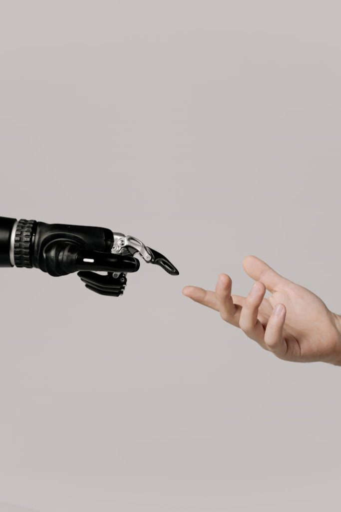 hand-of-a-person-and-a-bionic-hand-6153343 A human hand reaching to touch a bionic prosthetic hand on a white background.