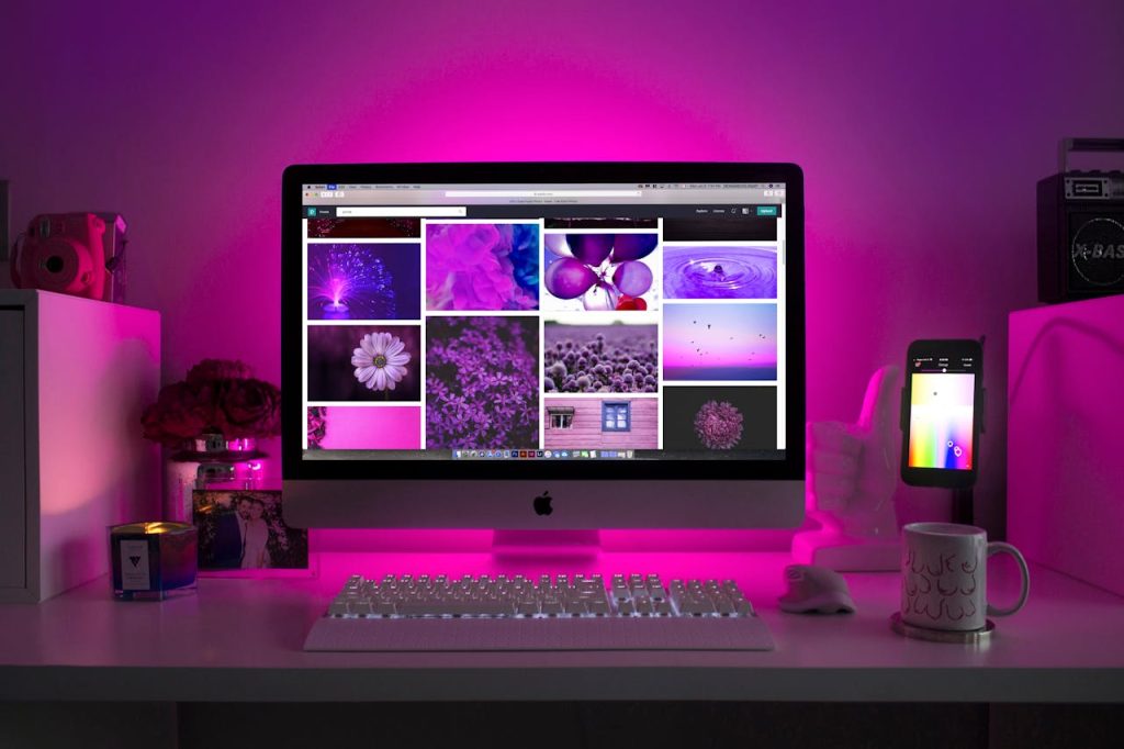 Bureau moderne avec éclairage néon et écran affichant un site web coloré, symbolisant la créativité digitale et le design web sur mesure
