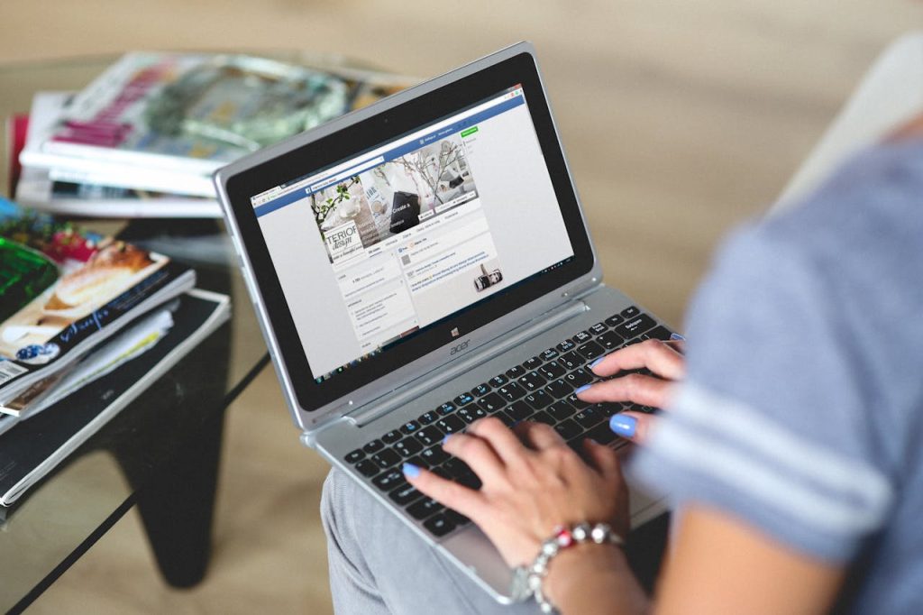 utilisatrice-reseaux-sociaux-site-web-automatisation Femme utilisant un ordinateur portable avec les réseaux sociaux à l’écran, illustrant la gestion digitale et l’intégration web